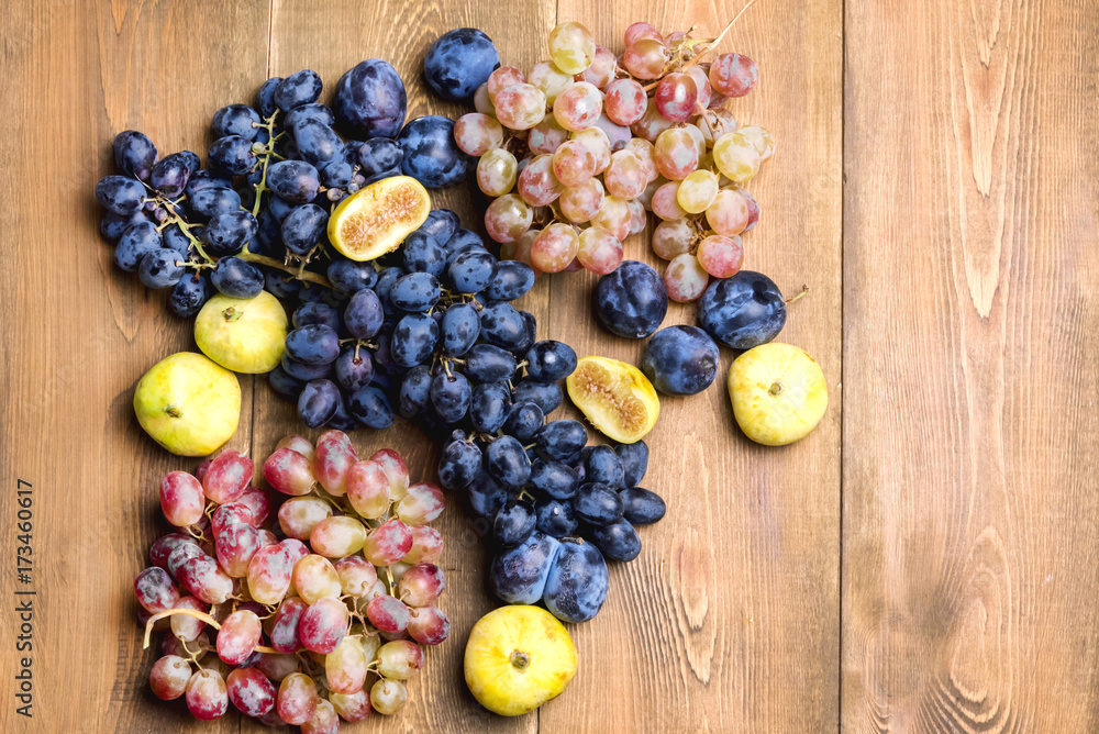 Bunches of fresh ripe grapes and figs on a wooden background Beautiful background with a branch of blue and red grapes. Figs Top view Bunches of fresh ripe grapes and figs on a wooden background Beautiful background with a branch of blue and red grapes. Figs Top view