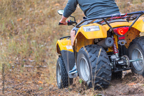 Man riding an ATV quadbike in a beautiful autumn pine forest with carpet of fallen needles