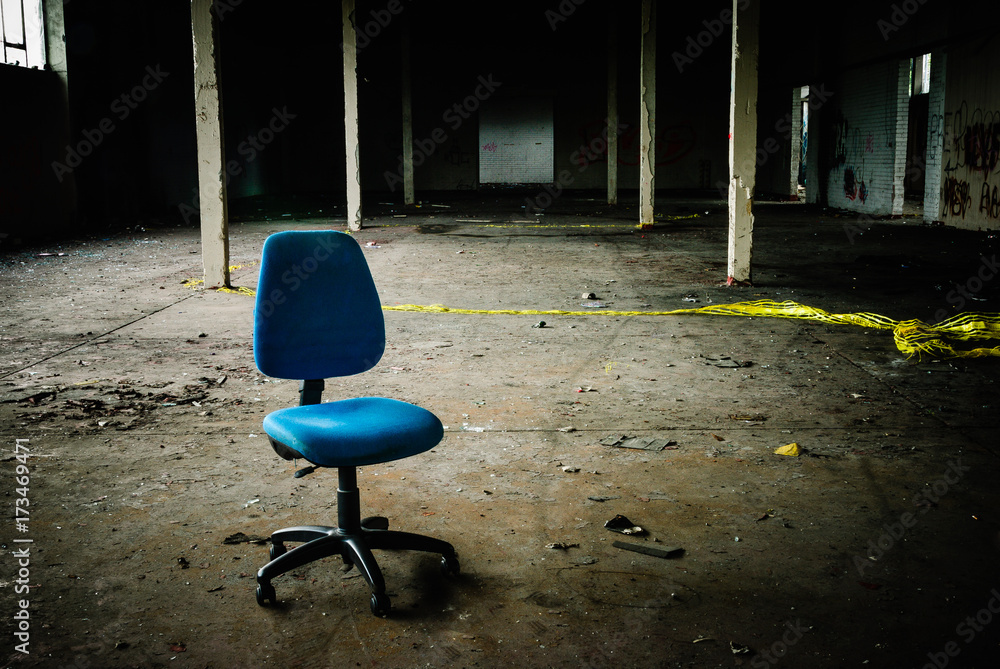 Office chair sits in the middle of an empty abandoned warehouse