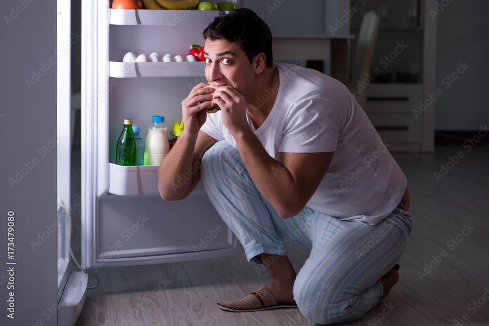 Man at the fridge eating at night Man at the fridge eating at night