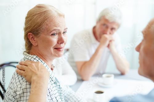 Crying senior female listening to her friend supporting her in grief