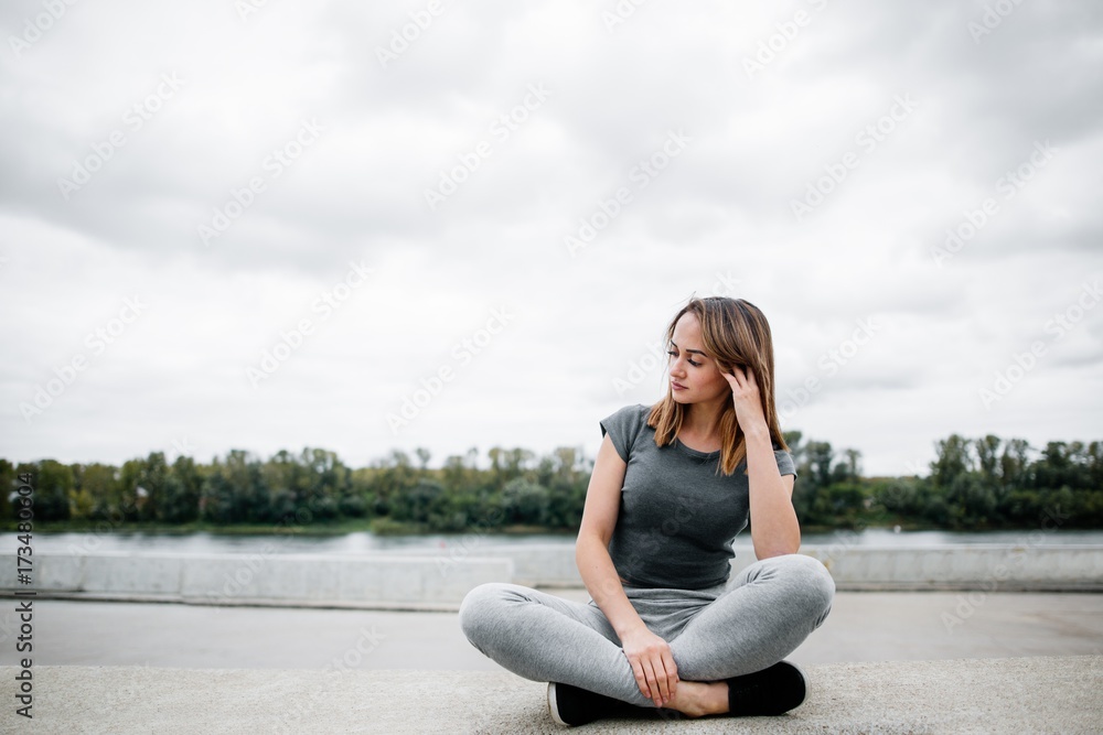 Pensive girl sitting on the background of the waterfront Pensive girl sitting on the background of the waterfront