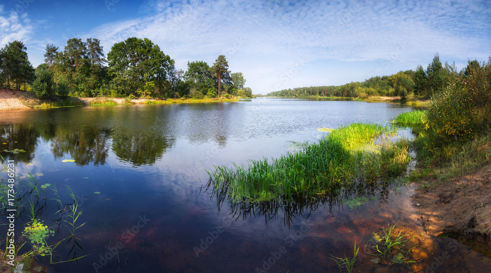 Beautiful landscape of the lake at sunny day. Panoramic view of the backwater and green coast with trees reflecting in the water. Beautiful landscape of the lake at sunny day. Panoramic view of the backwater and green coast with trees reflecting in the water.