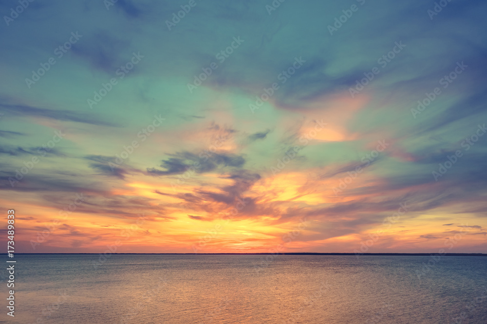 Aerial panoramic view of sunset over ocean. Nothing but sky, clouds and water. Dramatic picturesque evening scene. Ocean and colorful cloudy sky in the background. Nature landscape. Travel background