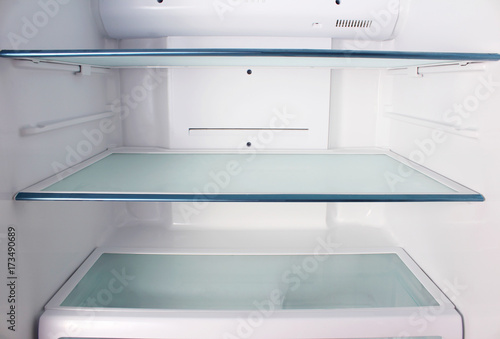 Inside the empty white refrigerator with shelves for where to place bottles of water, fruit , food ,