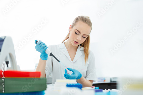 Pipette dropping a sample in a test tube. Laboratory assistant analyzing blood in lab. DNA analysis