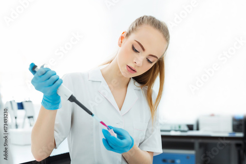 Pipette dropping a sample in a test tube. Laboratory assistant analyzing blood in lab. DNA analysis