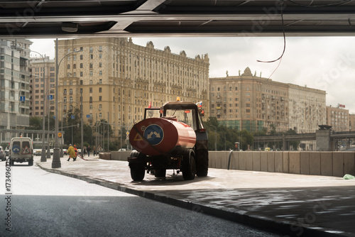Tractor with tank washes the asphalt under the bridge. Moscow photo