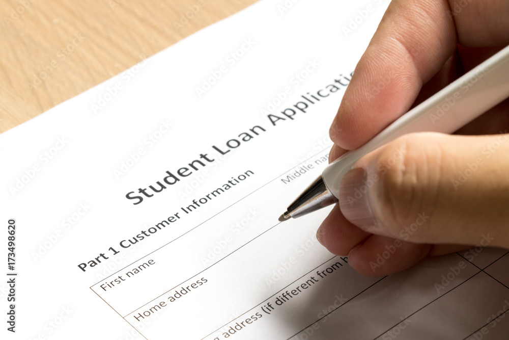 Man wait to fill information in student loan application form on desk background Man wait to fill information in student loan application form on desk background