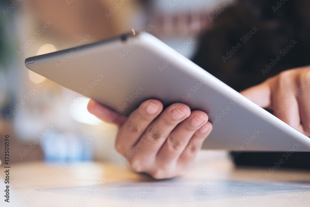A beautiful Asian woman's hands pointing , touching and using tablet pc with blur background in cafe A beautiful Asian woman's hands pointing , touching and using tablet pc with blur background in cafe