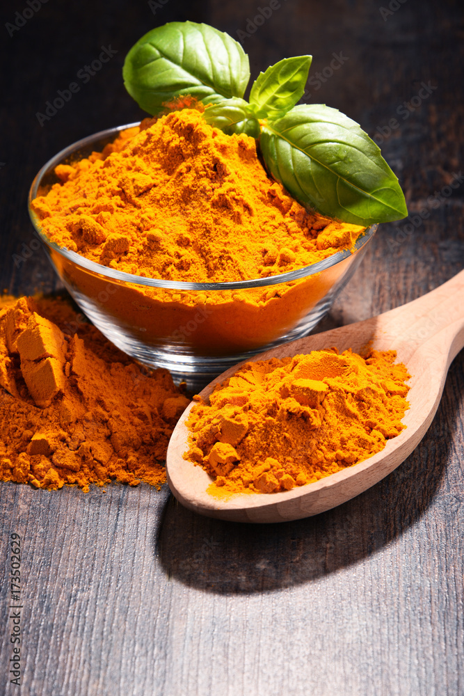 Composition with bowl of turmeric powder on wooden table Composition with bowl of turmeric powder on wooden table