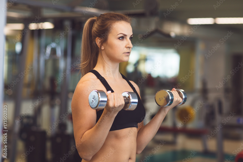 Young fitness girl lifting dumbbells in the gym Young fitness girl lifting dumbbells in the gym