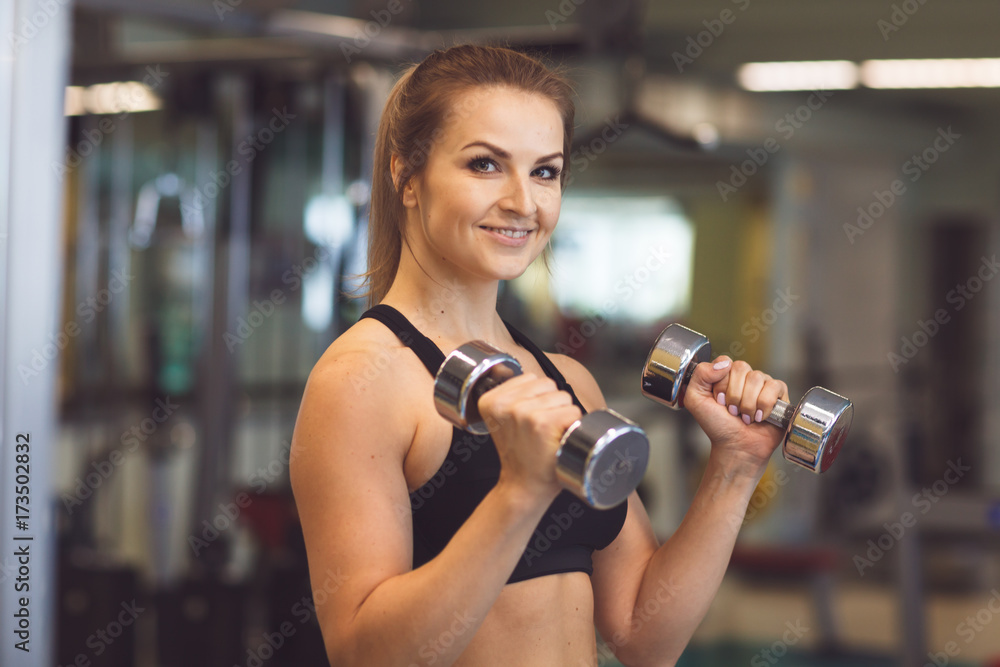 Young fitness girl lifting dumbbells in the gym Young fitness girl lifting dumbbells in the gym