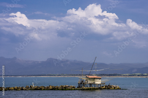 Trebuchet fishing hut against the Alps, Marina di Pisa, Tuscany, Italy, under a beautiful blue sky