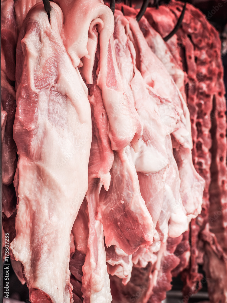 Fresh pork fillet hanging on display for sale at the butcher shop.