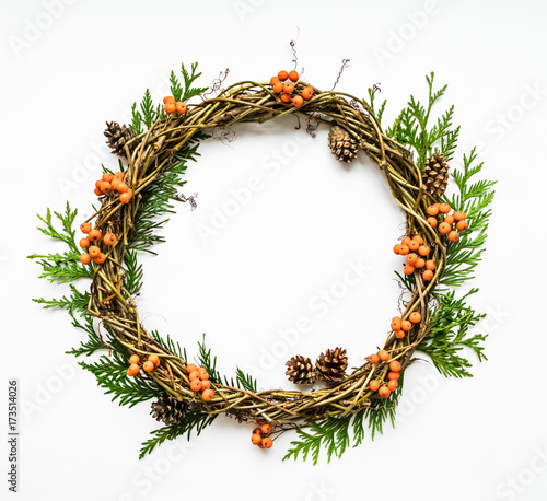 Festive wreath of vines with thuja branches, rowanberries and cones. Flat lay, top view photo