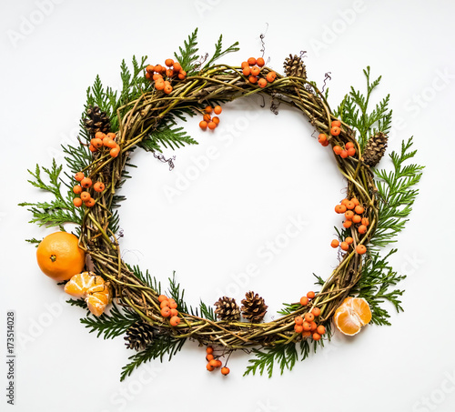 Festive wreath of vines with tangerines, thuja branches, rowanberries and cones. Flat lay, top view