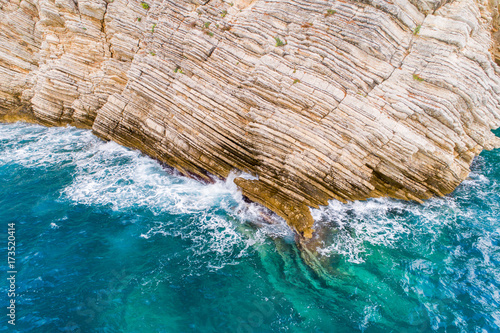 A bird's-eye view of how turquoise waves beat about sea cliffs in Montenegro