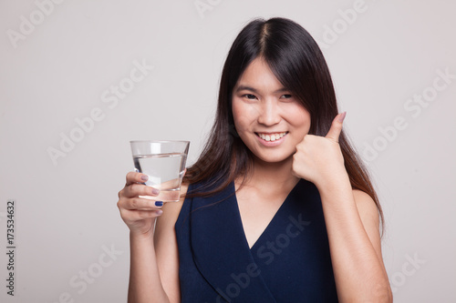 Young Asian woman thumbs up with a glass of drinking water.