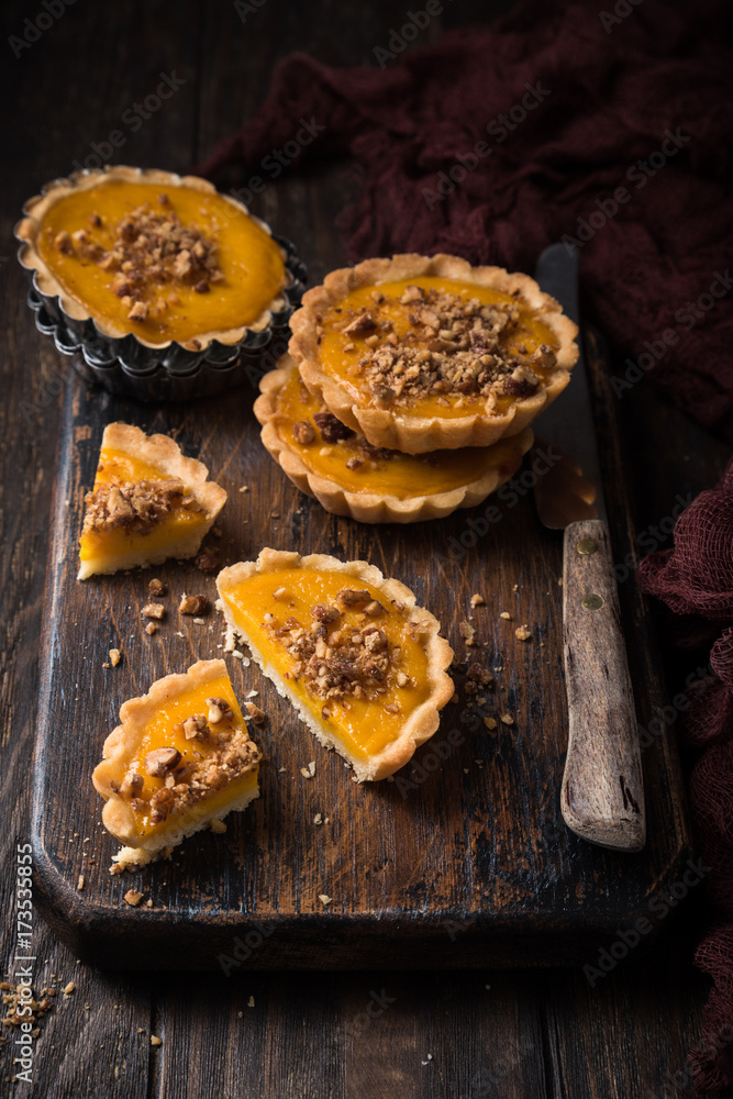 Pumpkin mini pie, tartlet made for Thanksgiving day on old wooden background. Healthy autumn food concept with copy space. Dark photo.