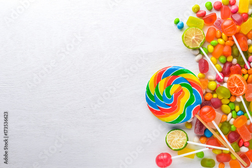 Colored candies, sweets and lollipops. On a white wooden background. Top view. Free space.