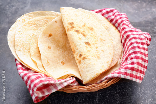 Wicker basket with delicious tortillas on table photo