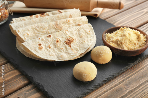 Slate plate with delicious tortillas on wooden table