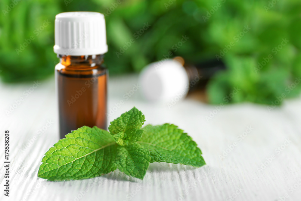 Bottle of essential oil and mint on wooden table Bottle of essential oil and mint on wooden table