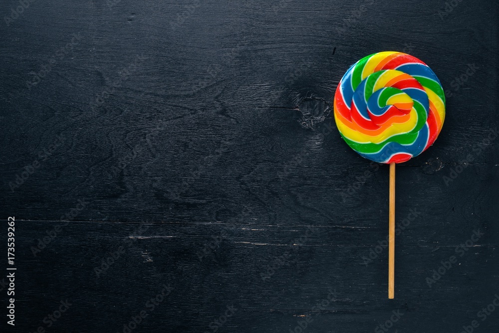 Colored candies, sweets and lollipops. On a black wooden background. Top view. Free space. Colored candies, sweets and lollipops. On a black wooden background. Top view. Free space.