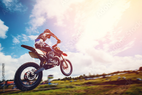 Racer on motorcycle participates and jumps. Close-up. concept of extreme motocross, sports racing. ray of light