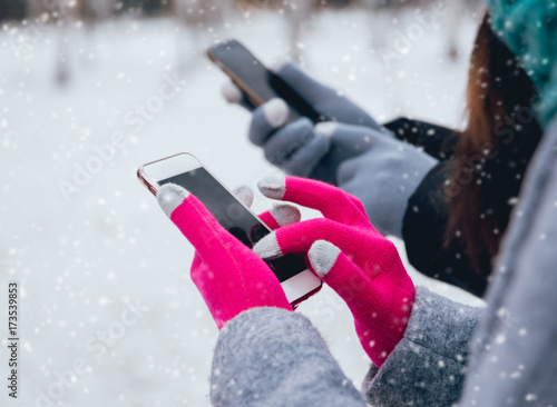 Couple using smartphone in winter with gloves for touch screens