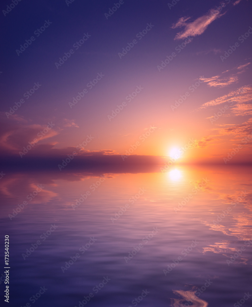 A pink and purple sunset against a background of clear sky and small clouds over the sea waters.