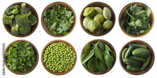 Top view. Fresh green vegetables and herbs isolated on a white background. Squash, brocoli, green peas, cucumbers and leaves parsley, celery, cilantro, spinach in wooden bowl with copy space for text.