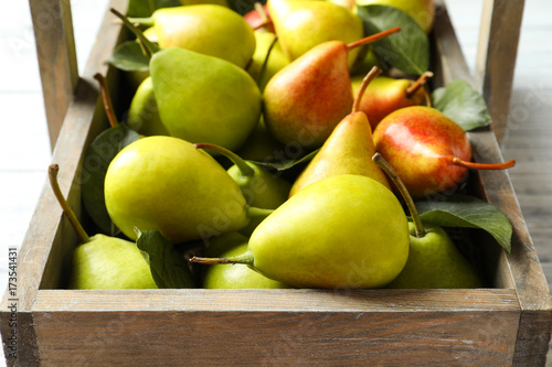 Ripe pears in wooden basket on light background