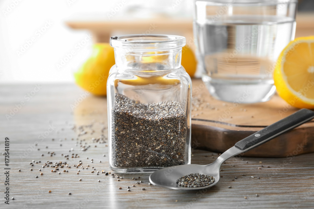 Chia seeds in glass jar and spoon on kitchen table Chia seeds in glass jar and spoon on kitchen table