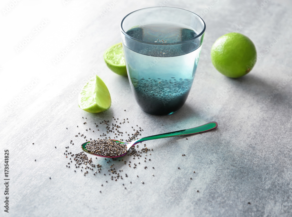Composition with chia seeds, lime and glass of water on light background Composition with chia seeds, lime and glass of water on light background