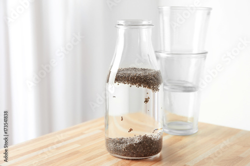 Chia seeds in bottle of water on wooden table