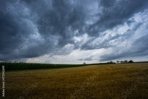 Thunderstorm with dramatic sky and cloud formations over harvested grainfield