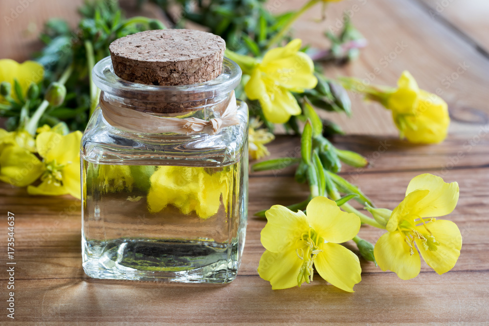A bottle of evening primrose oil with evening primrose flowers A bottle of evening primrose oil with evening primrose flowers
