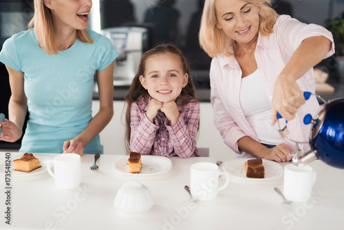 Two women and a girl getting ready to drink tea with a homemade pie in their kitchen