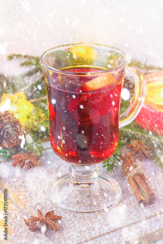 New Year's mulled wine in a glass on the background of twigs, candles and garlands.