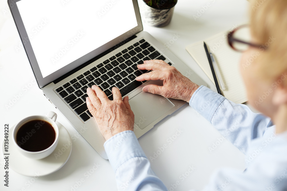 Back view of senior female with blonde short hairstyle using laptop pc for remote work. Cropped portrait of elderly manager working at office on portable computer with blank copy space screen Back view of senior female with blonde short hairstyle using laptop pc for remote work. Cropped portrait of elderly manager working at office on portable computer with blank copy space screen