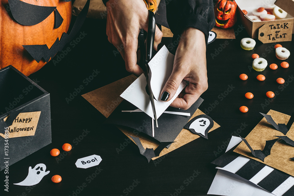 Obraz premium Halloween preparation. Hands making halloween decoration using craft paper