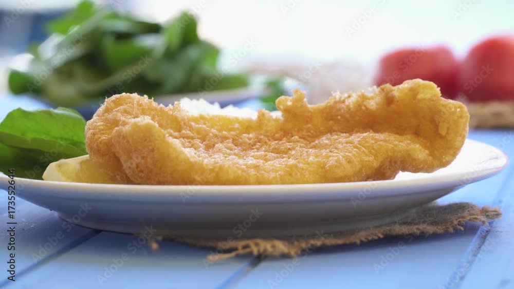 Fried seafood with lemon and arugula on blue table by the sea and small boats at small town. Fried seafood with lemon and arugula on blue table by the sea and small boats at small town.