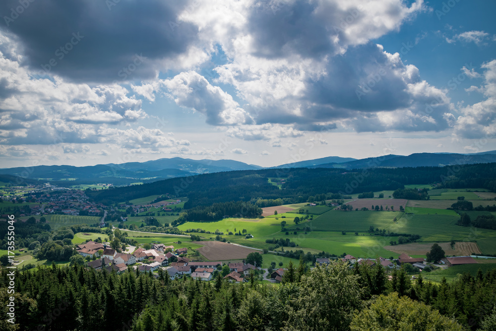 Blick in den Bayerischen Wald mit Wolken am Himmel und Sonnenstrahlen und Feldern