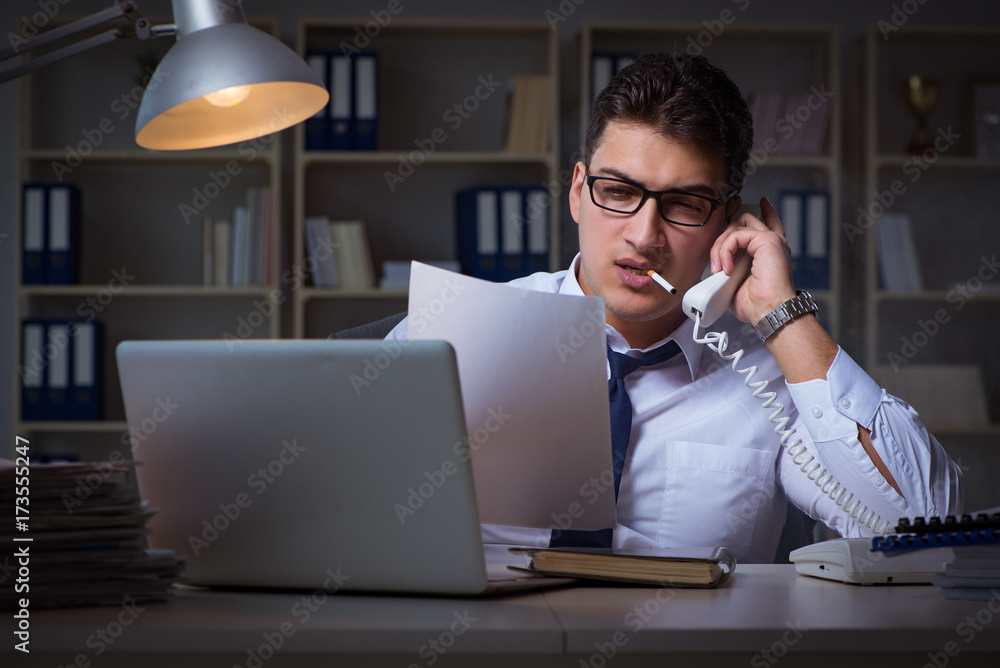 Businessman speaking on phone and smoking in office Businessman speaking on phone and smoking in office