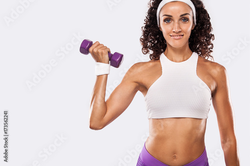 Sporty beautiful woman with dumbbell exercising at white background to stay fit