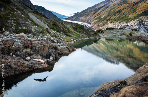 Young woman skinny dipping in calm pool in the Canadian mountains