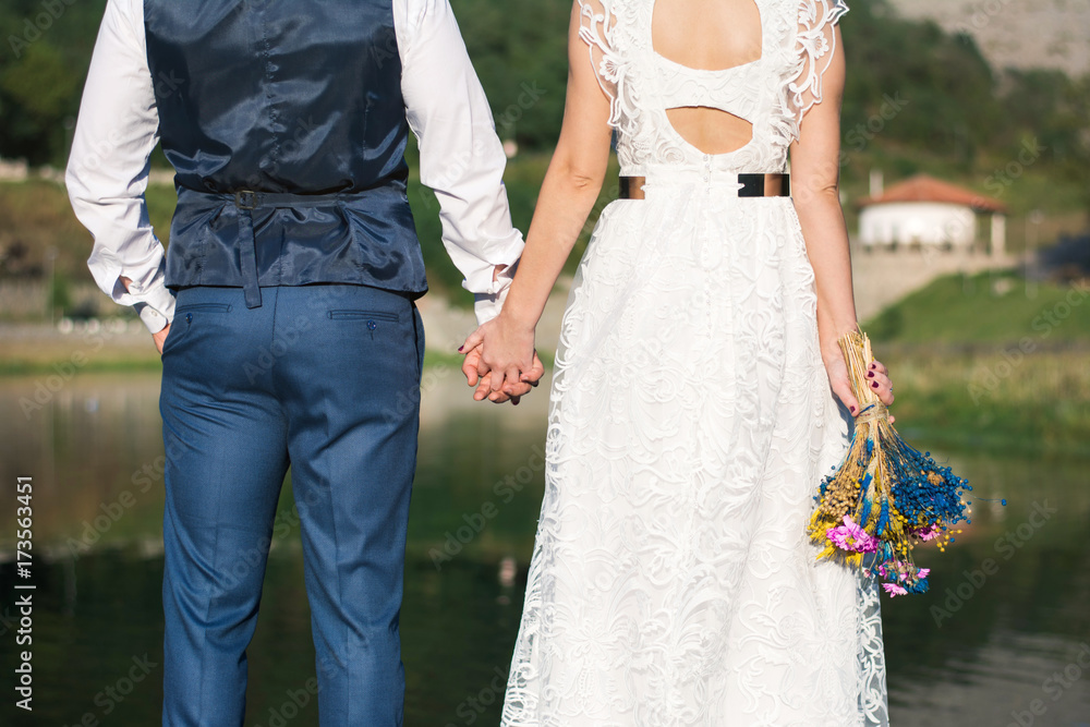 Wedding couple holding hands in front of a lake Wedding couple holding hands in front of a lake