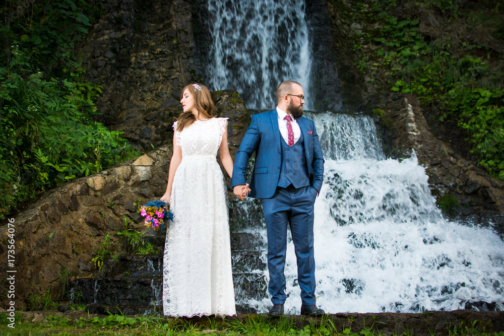 Wedding couple standing in front of a waterfall